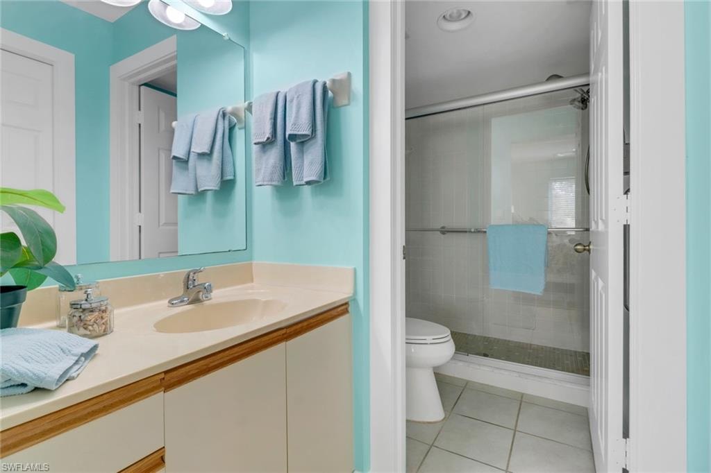 Full bathroom featuring toilet, tile patterned floors, vanity, and a stall shower
