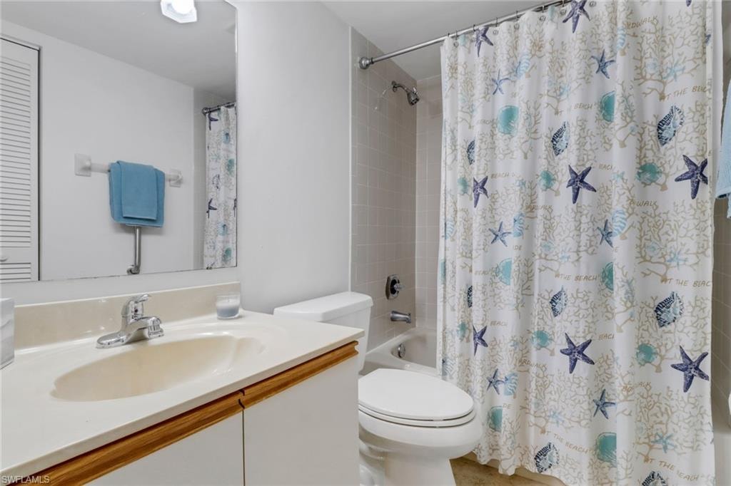 Bathroom with toilet, vanity, and shower / bath combo with shower curtain
