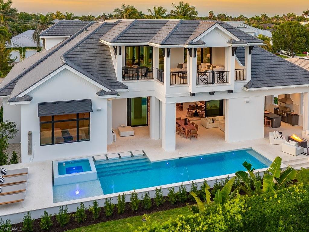 Rear view of house featuring an outdoor pool, stucco siding, a tiled roof, a balcony, and a patio area