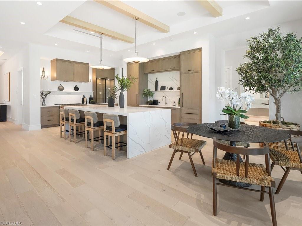 Kitchen featuring light countertops, beam ceiling, a spacious island, light wood-type flooring, and a breakfast bar area