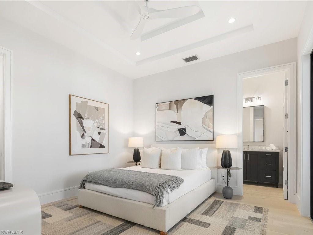 Bedroom featuring visible vents, baseboards, recessed lighting, a raised ceiling, and light wood-style floors