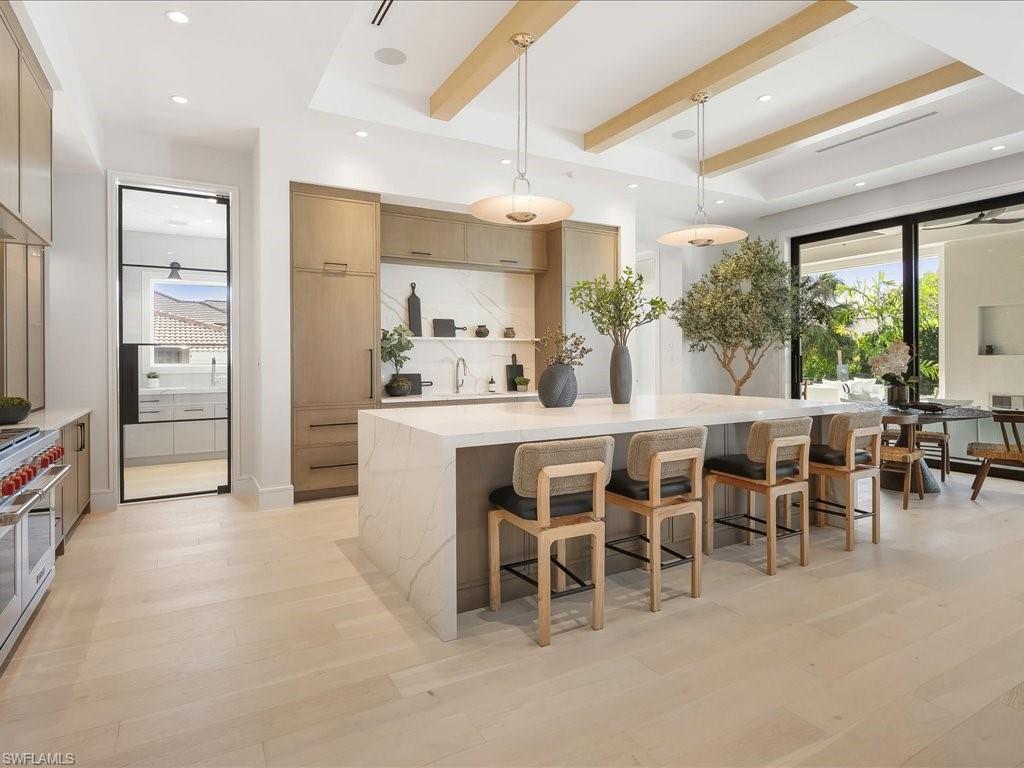 Kitchen with double oven range, modern cabinets, beamed ceiling, and light wood finished floors