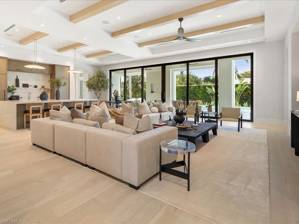 Living area with beamed ceiling, baseboards, recessed lighting, a ceiling fan, and light wood-type flooring