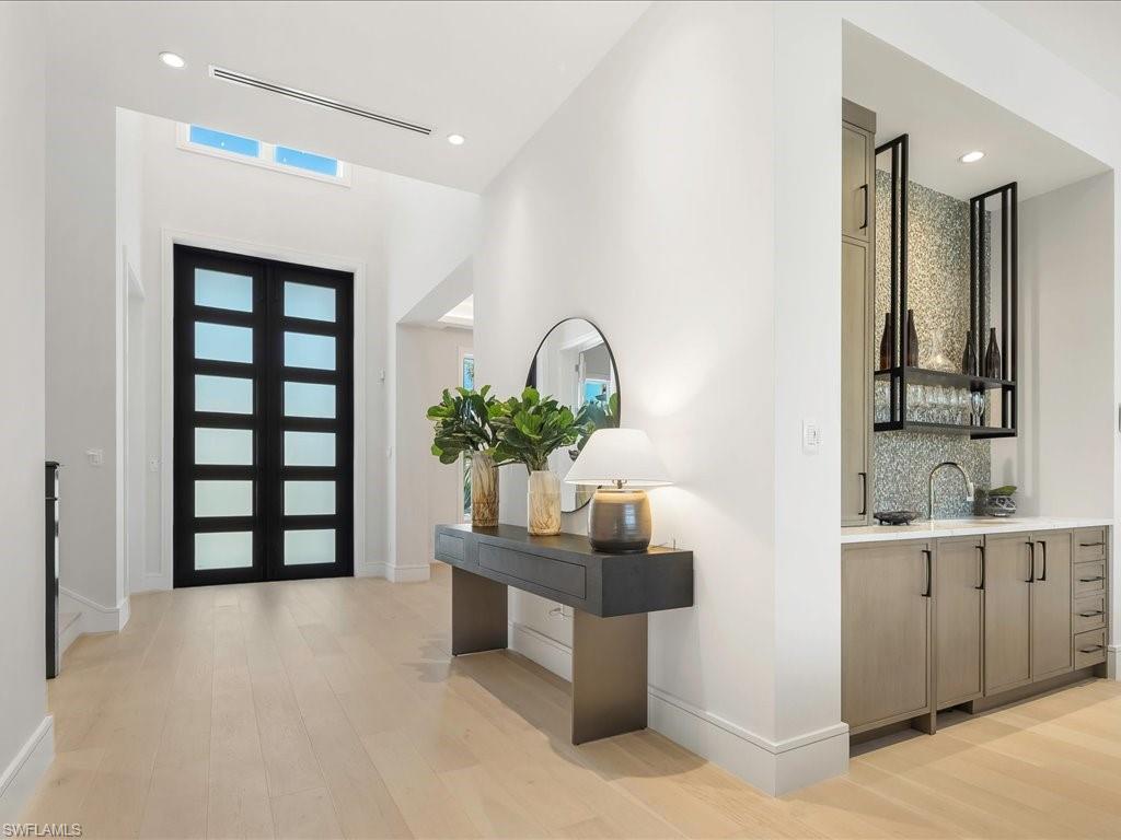 Foyer entrance with visible vents, light wood-style flooring, baseboards, recessed lighting, and wet bar