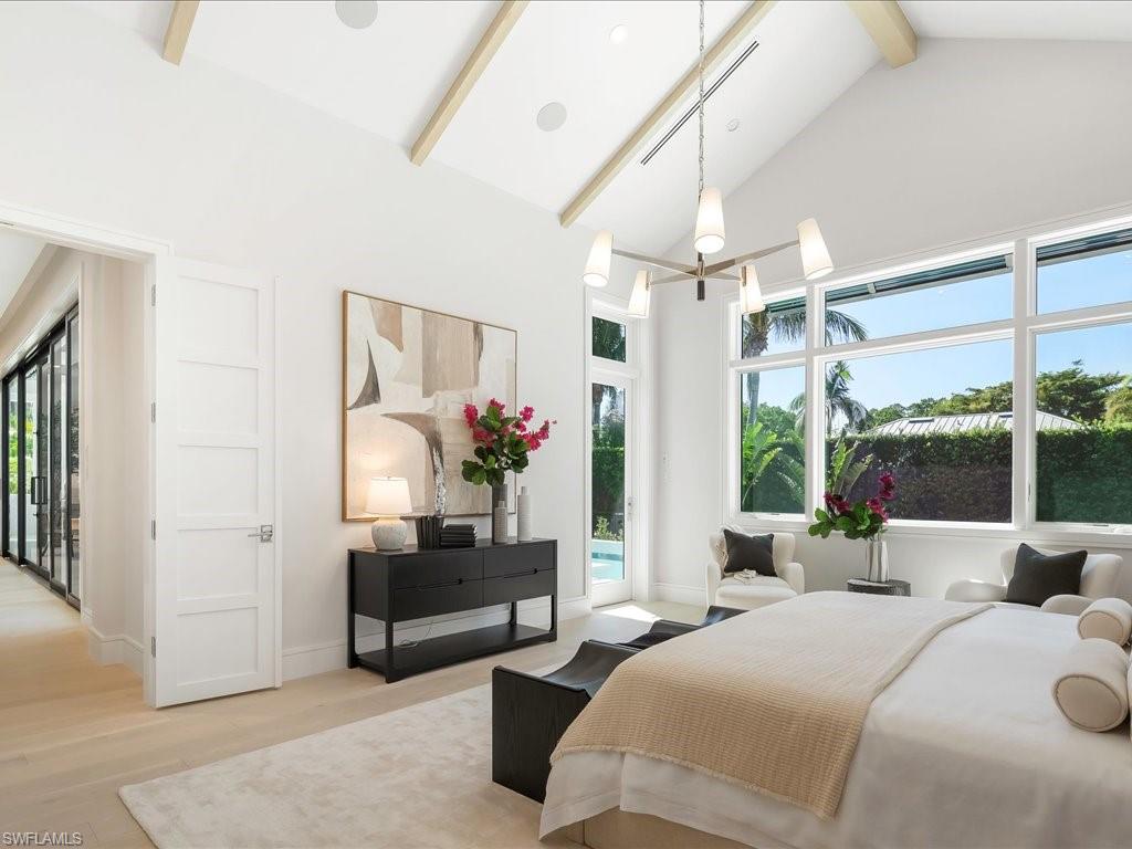 Bedroom featuring high vaulted ceiling, beam ceiling, access to exterior, light wood-style floors, and an inviting chandelier