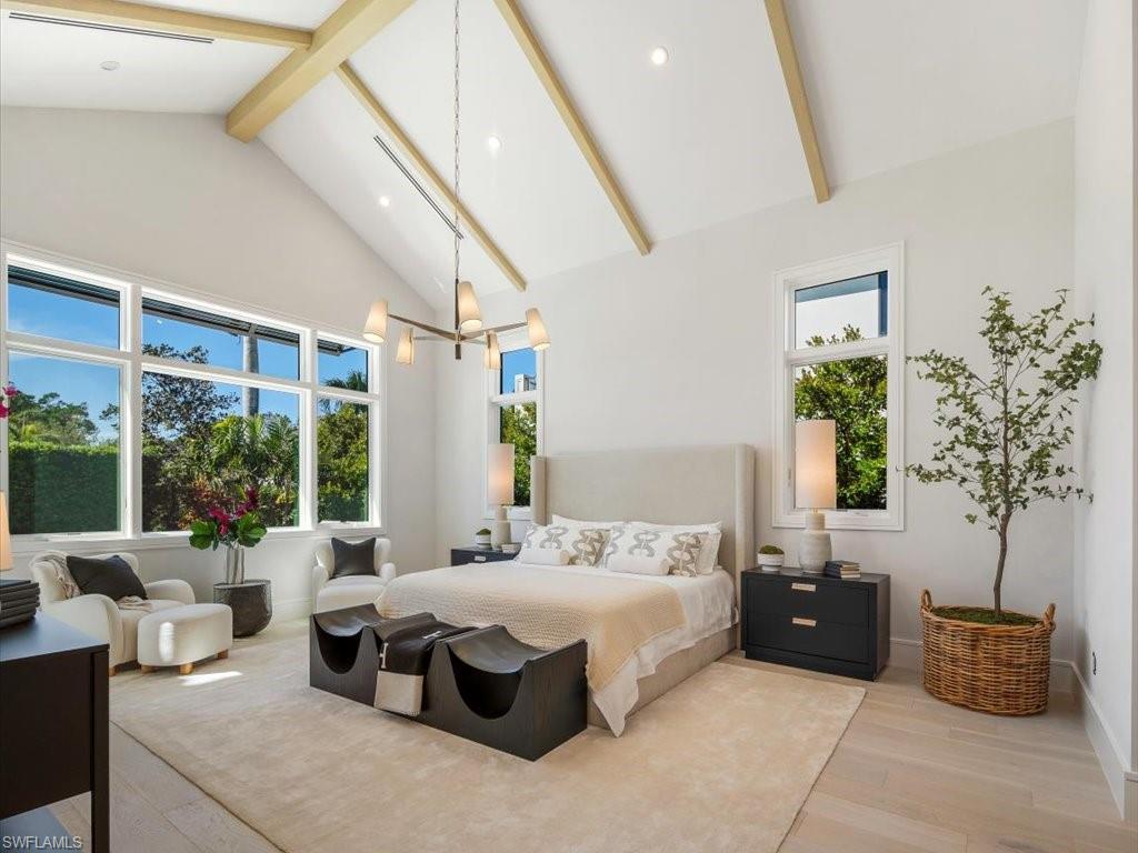 Bedroom with high vaulted ceiling, a chandelier, baseboards, wood finished floors, and beam ceiling