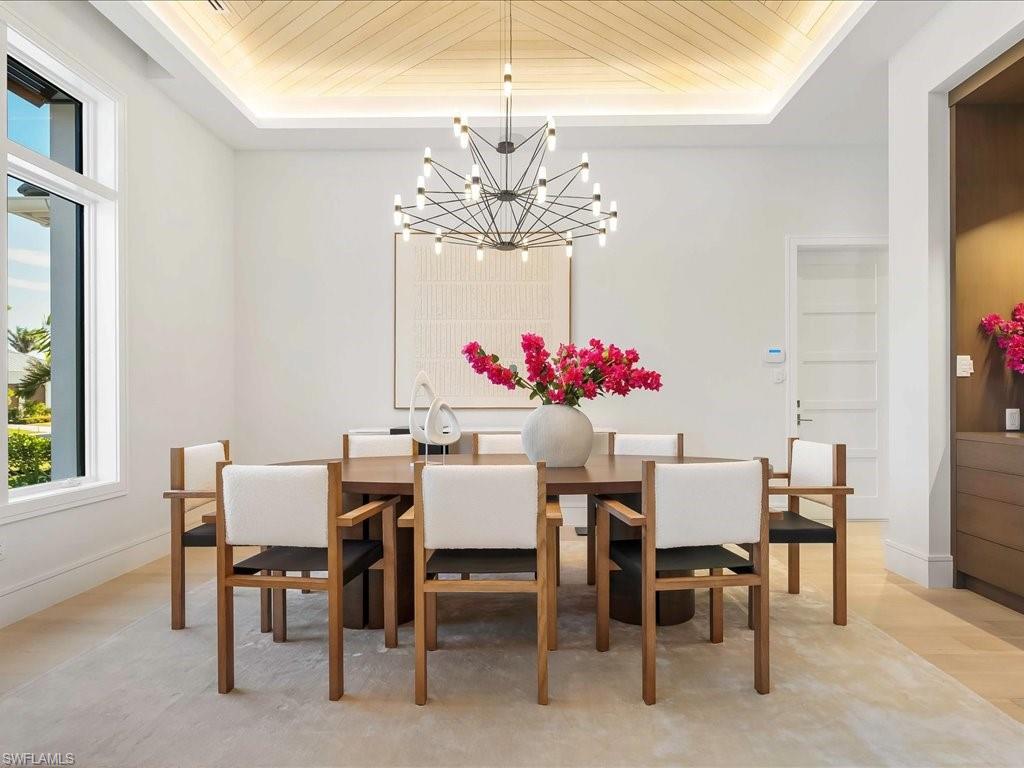 Dining room featuring a notable chandelier, a tray ceiling, light wood-type flooring, and wooden ceiling