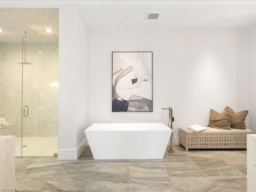 Bathroom with baseboards, a soaking tub, marble finish floor, a stall shower, and visible vents