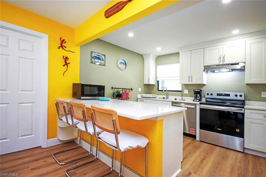 Kitchen with white cabinets, a breakfast bar, appliances with stainless steel finishes,