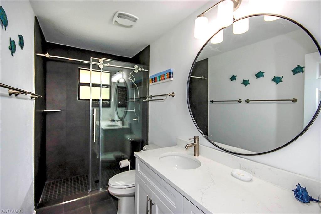 Full bathroom with a stall shower, visible vents, toilet, and vanity