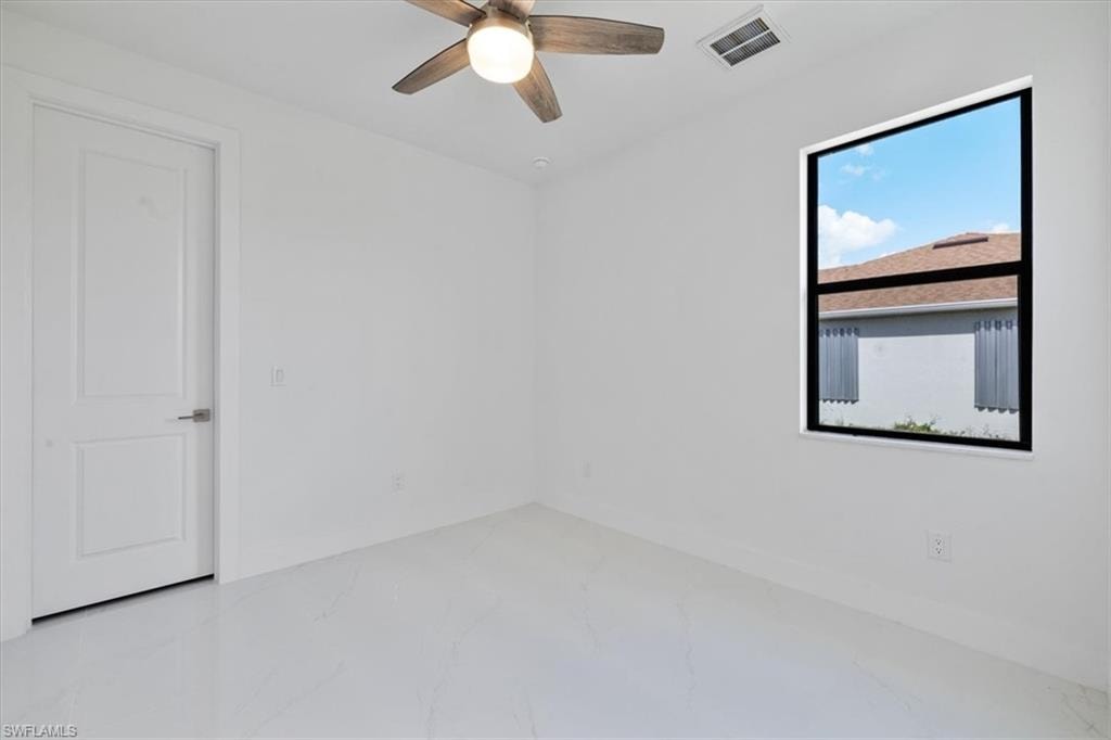 Spare room with a ceiling fan, marble finish floor, and visible vents