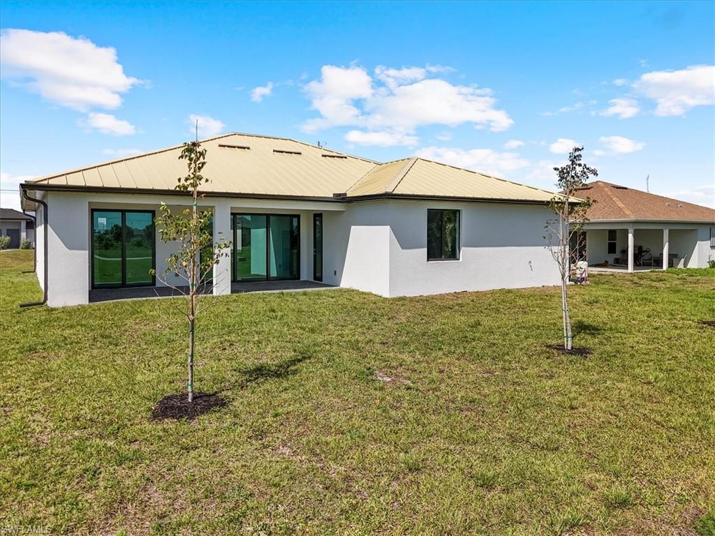 Back of house featuring stucco siding and a lawn