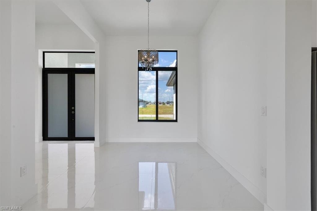 Unfurnished room with baseboards, marble finish floor, and a notable chandelier