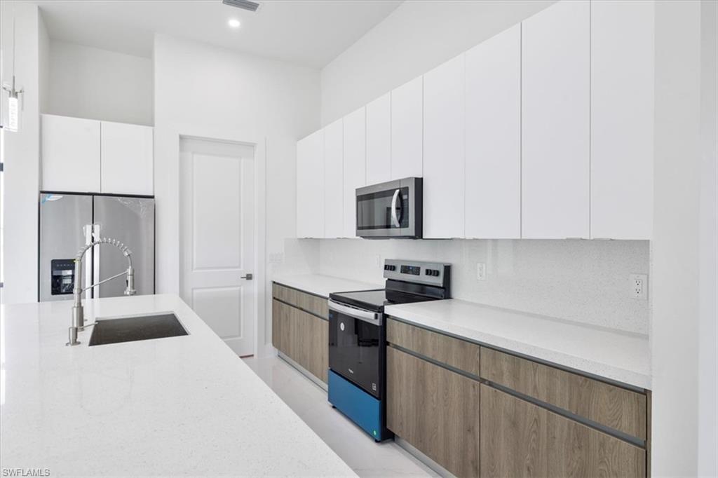 Kitchen with white cabinets, a sink, modern cabinets, and appliances with stainless steel finishes