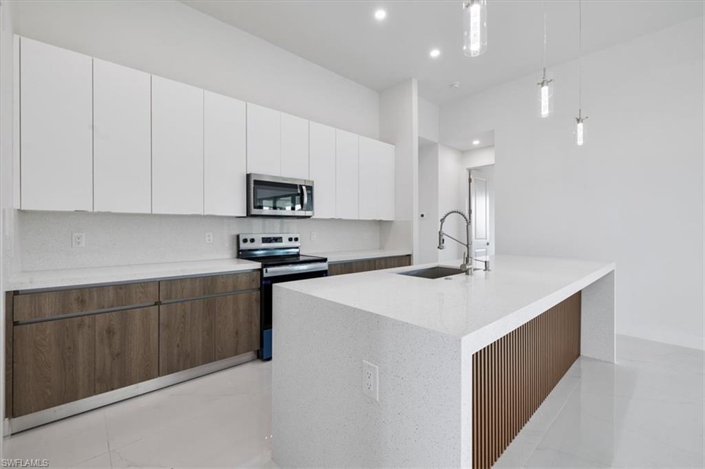 Kitchen with white cabinets, modern cabinets, stainless steel appliances, tasteful backsplash, and a sink