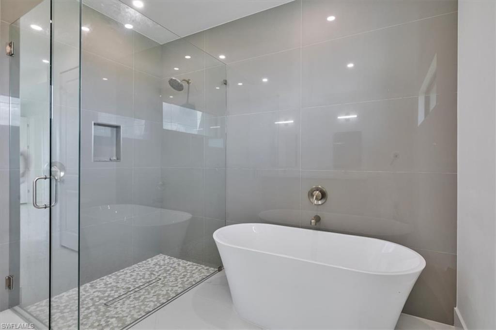 Full bath with a shower stall, a soaking tub, and tile walls