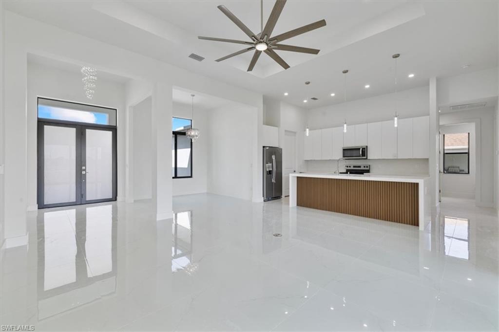 Kitchen featuring open floor plan, white cabinetry, stainless steel appliances, a raised ceiling, and modern cabinets
