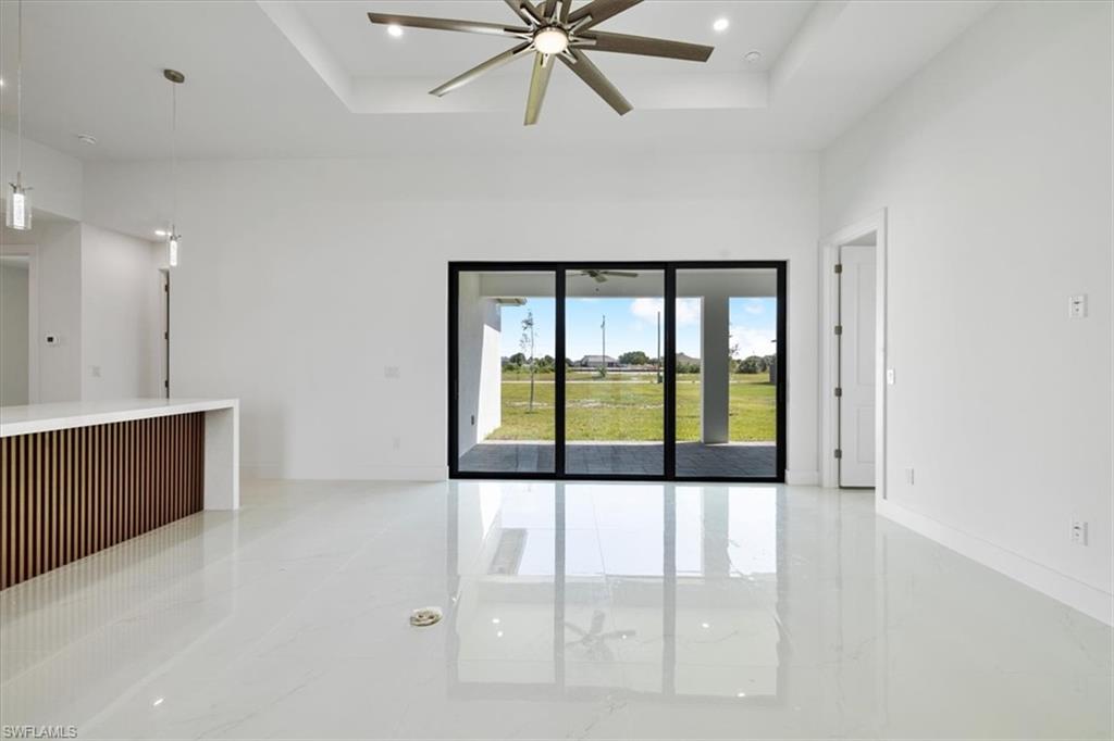 Empty room featuring a tray ceiling, marble finish floor, ceiling fan, and a towering ceiling