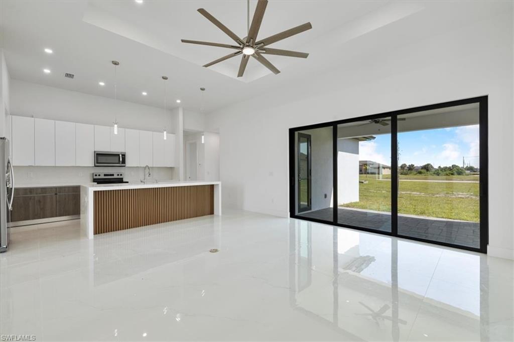 Kitchen with a ceiling fan, appliances with stainless steel finishes, modern cabinets, open floor plan, and white cabinets
