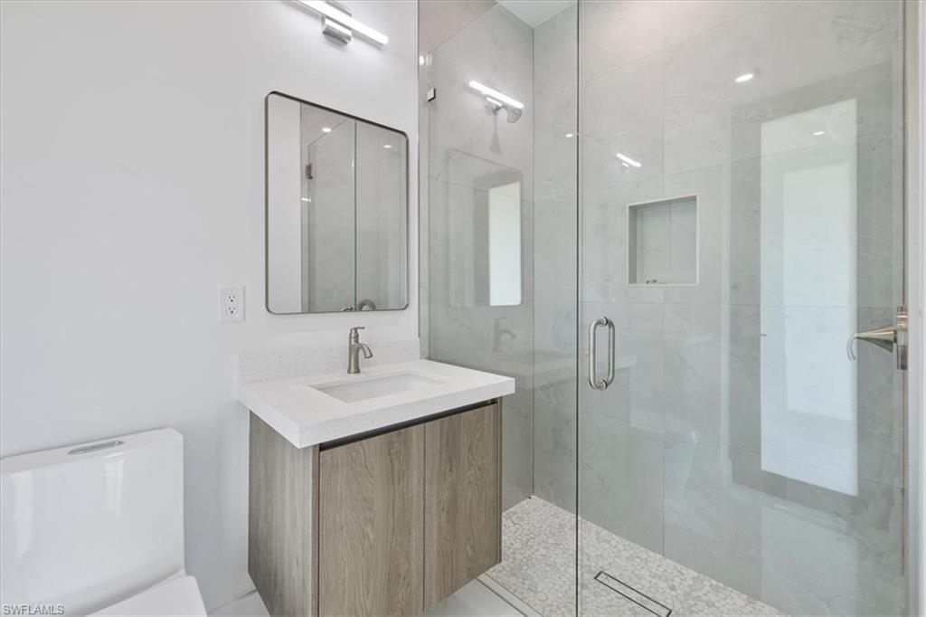 Full bath with a stall shower, toilet, and vanity