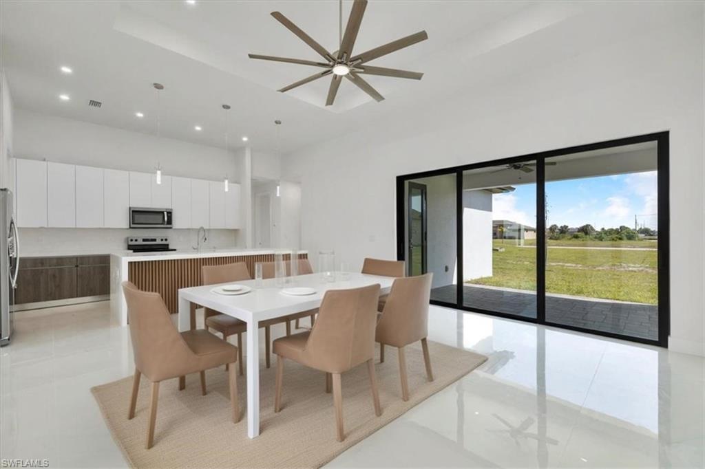 Dining area with a high ceiling, a ceiling fan, visible vents, and recessed lighting