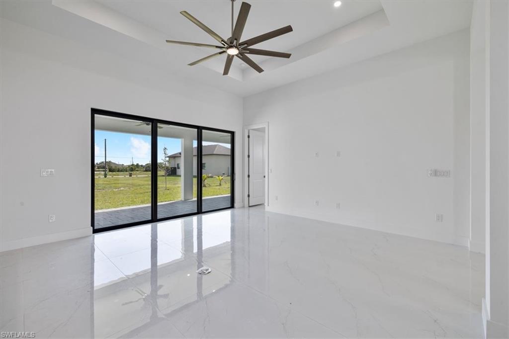 Spare room with marble finish floor, baseboards, a ceiling fan, and a raised ceiling