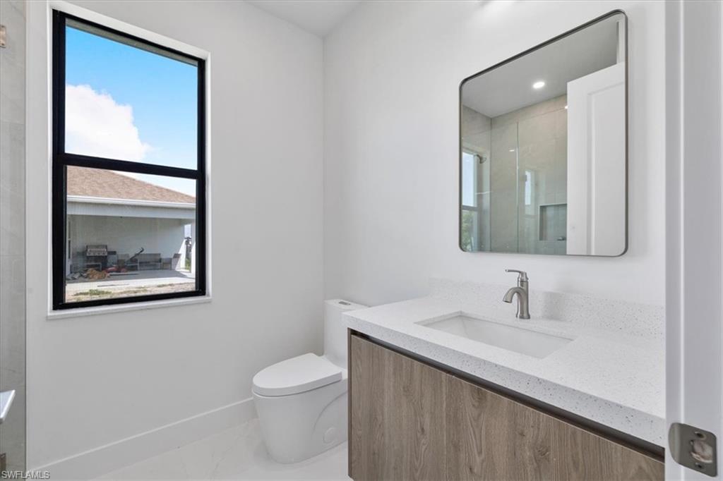 Bathroom featuring an enclosed shower, baseboards, toilet, and vanity