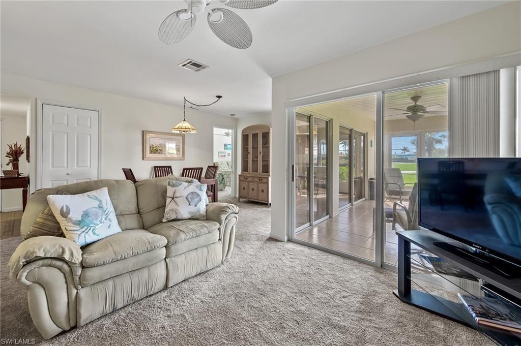 Living area featuring visible vents, a ceiling fan, and carpet