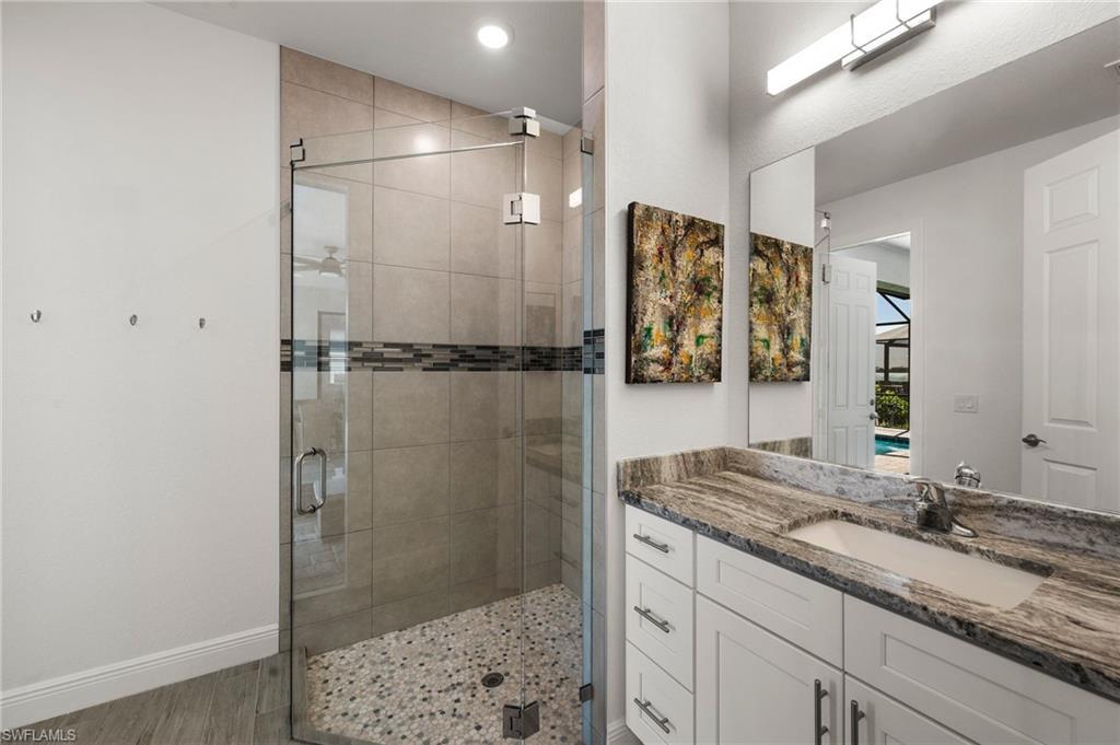 Full bath with baseboards, a shower stall, vanity, and wood finished floors