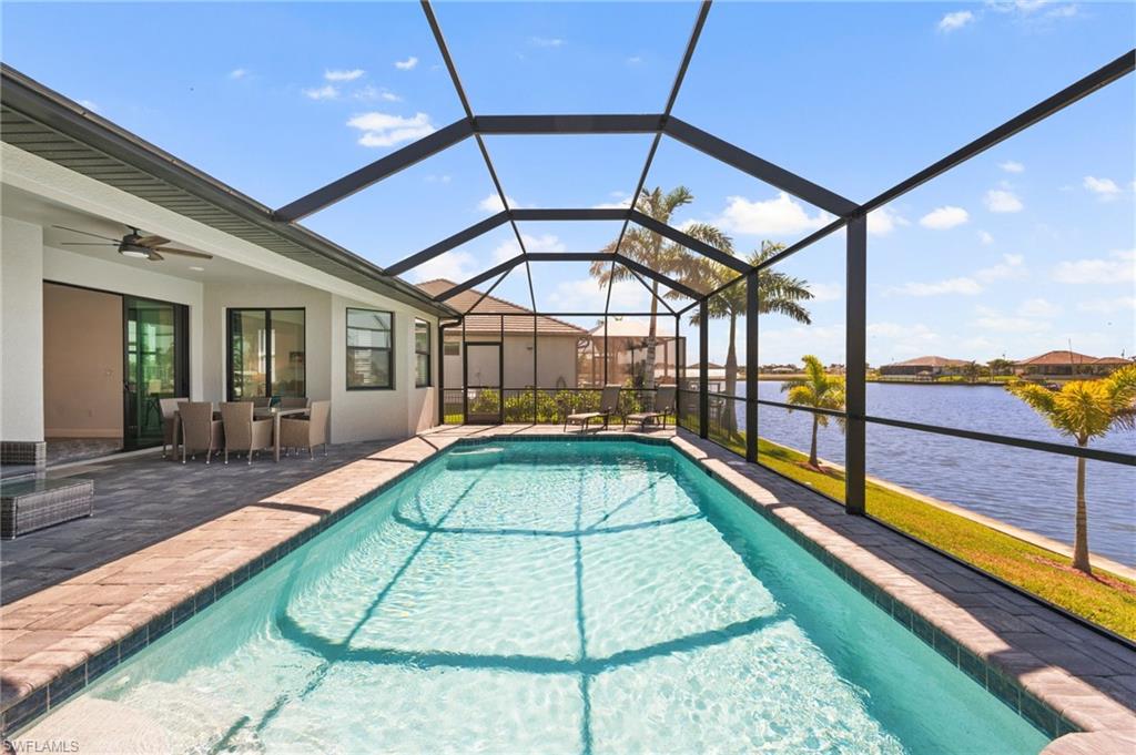 Outdoor pool with a patio area, a ceiling fan, a water view, and a lanai