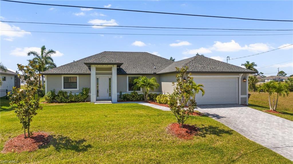 View of front of house featuring a front yard, an attached garage, stucco siding, decorative driveway, and roof with shingles