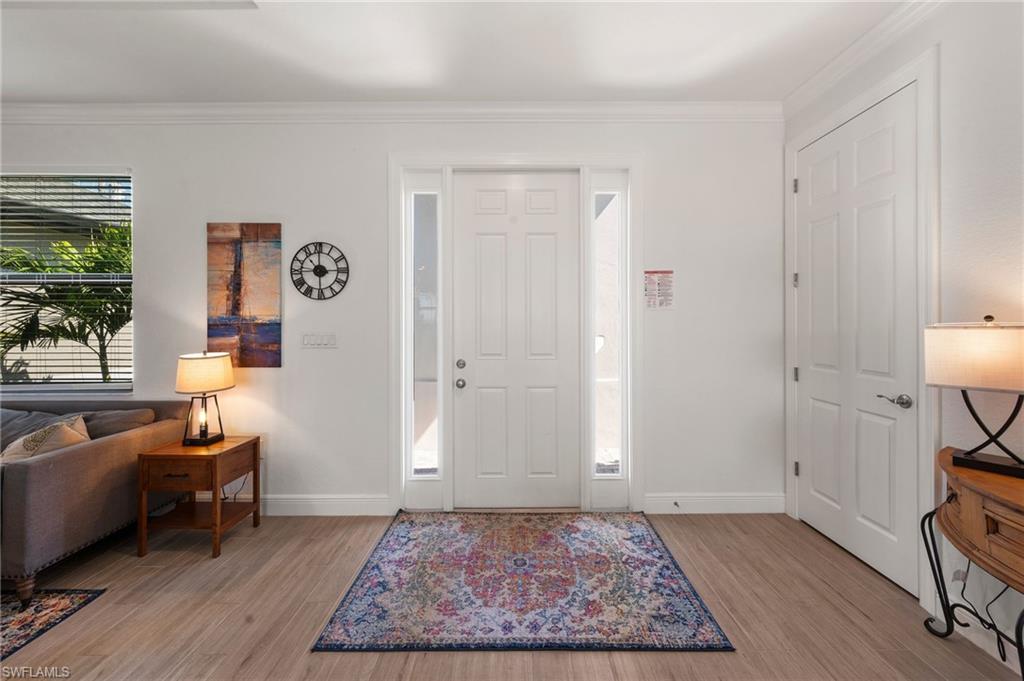 Entryway featuring wood finished floors, baseboards, and ornamental molding