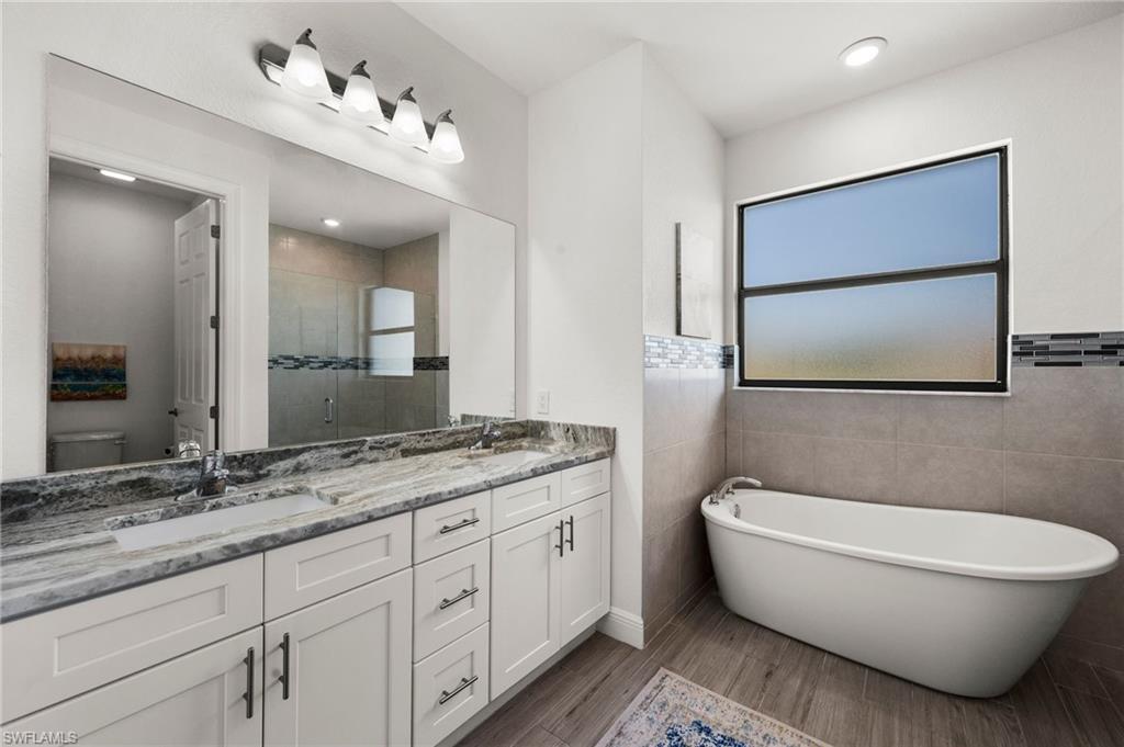 Full bathroom featuring a shower stall, double vanity, a sink, and toilet