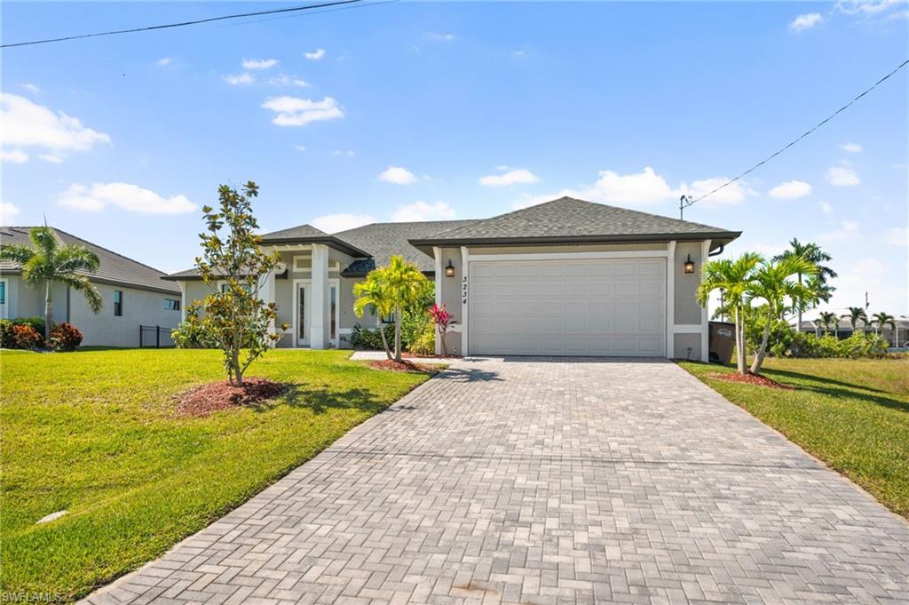 View of front of property with a front yard, a garage, decorative driveway, and stucco siding