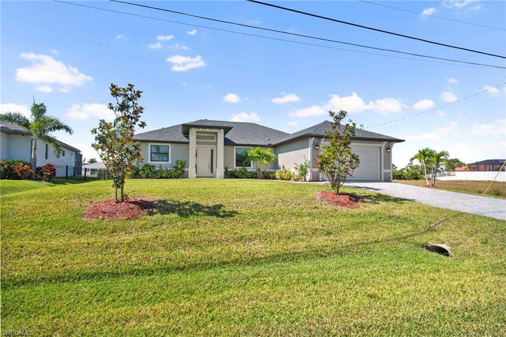 Prairie-style home with an attached garage, stucco siding, decorative driveway, and a front lawn