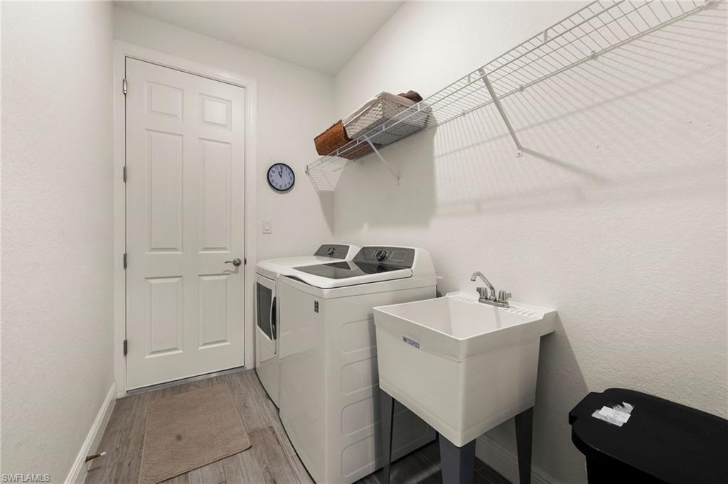 Laundry room with laundry area, light wood-type flooring, a sink, washer and dryer, and baseboards