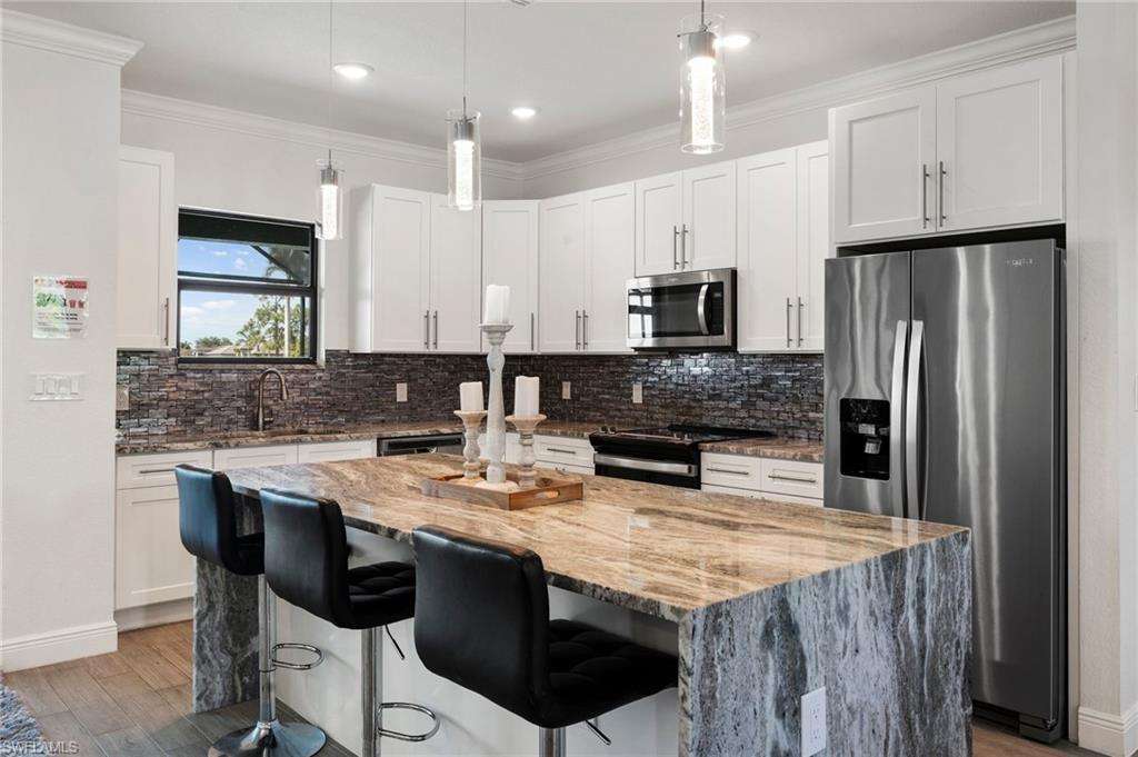Kitchen featuring ornamental molding, a center island, appliances with stainless steel finishes, and backsplash