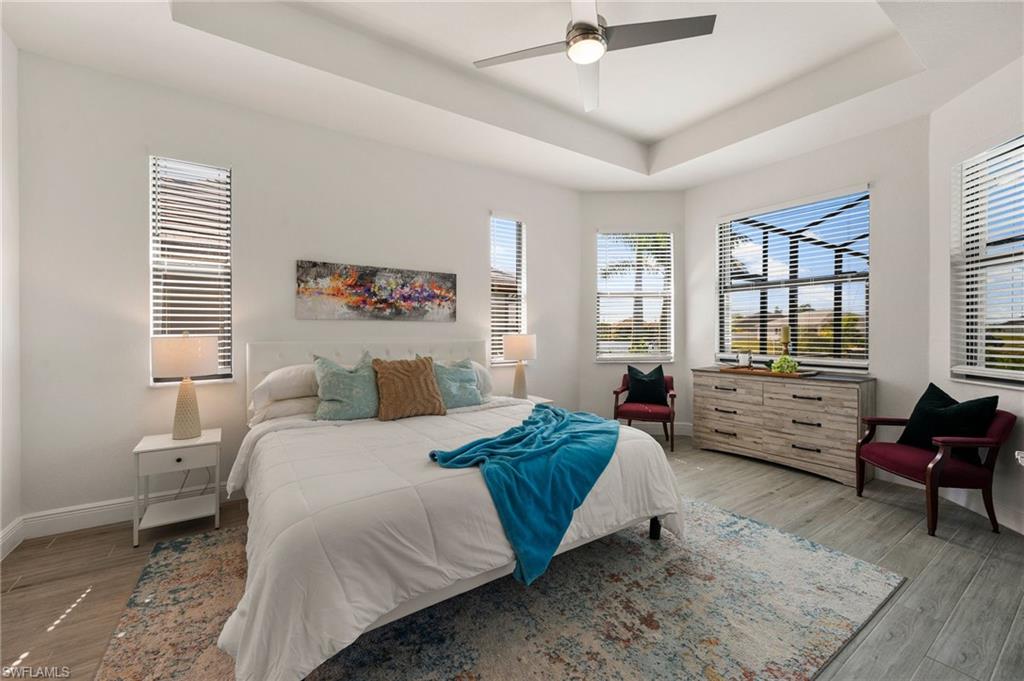 Bedroom featuring baseboards, a raised ceiling, ceiling fan, and wood finished floors
