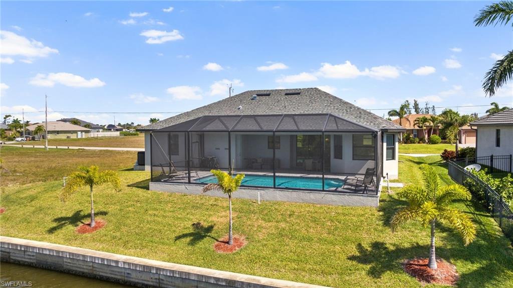 Back of property with glass enclosure, a fenced in pool, a patio, and a lawn