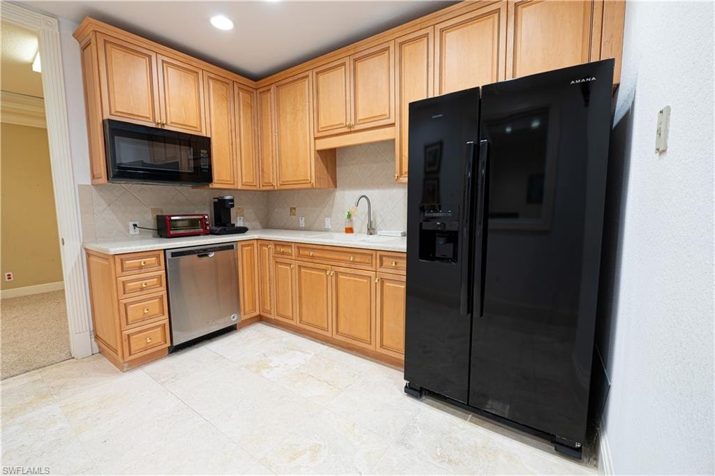 Kitchen featuring baseboards, a sink, light countertops, black appliances, and backsplash