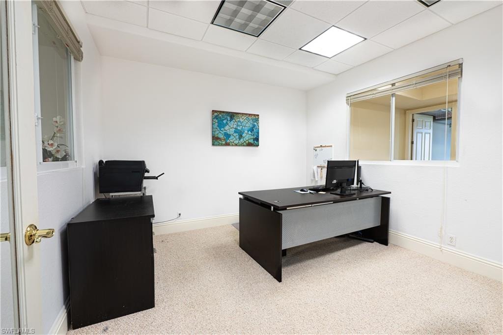 Office area featuring carpet flooring, baseboards, a drop ceiling, and visible vents