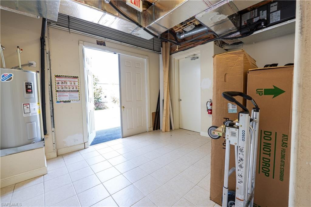 Below grade area featuring tile patterned flooring and electric water heater