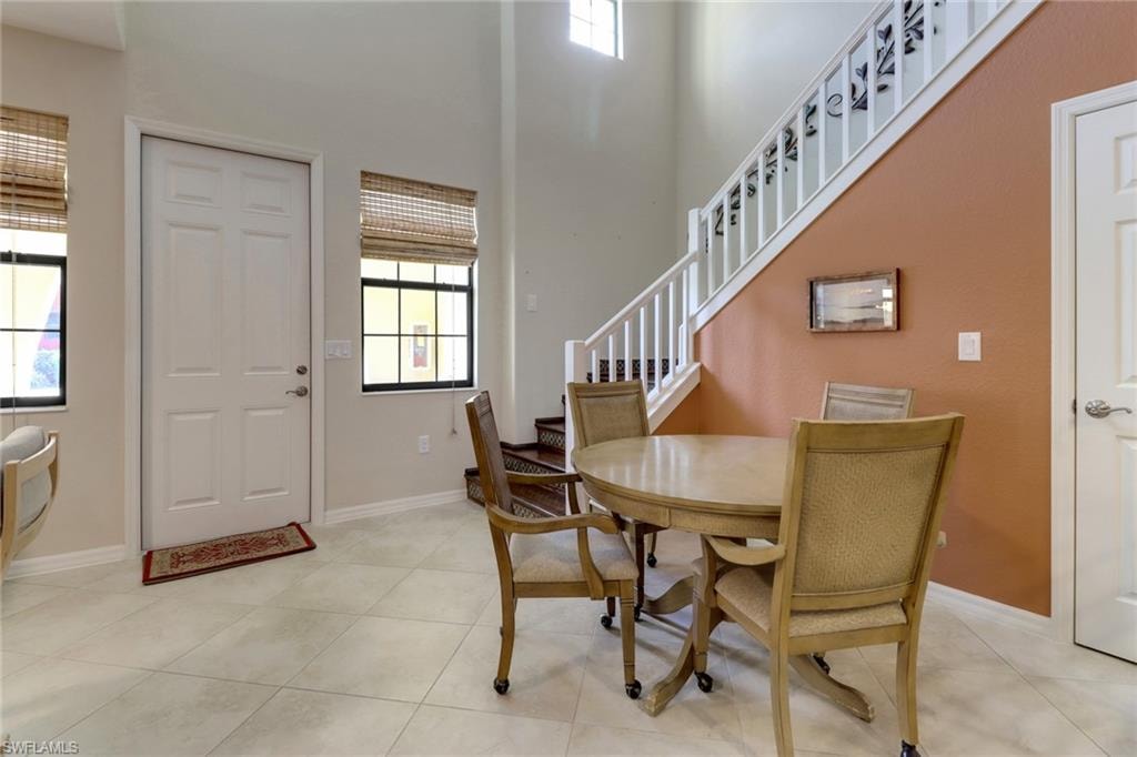Dining space featuring light tile patterned floors, baseboards, and stairs
