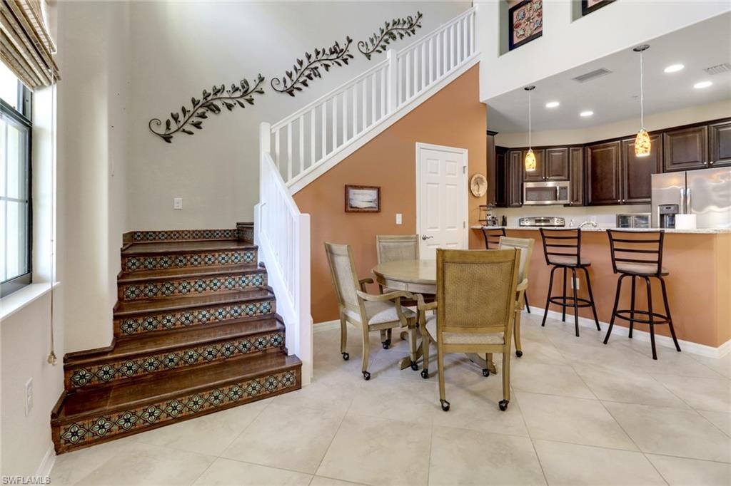 Dining room featuring recessed lighting, stairs, and a high ceiling