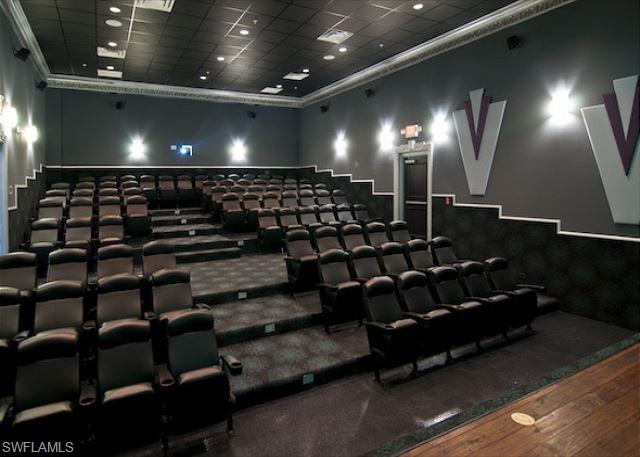 Home theater with a drop ceiling, wood finished floors, a high ceiling, and ornamental molding