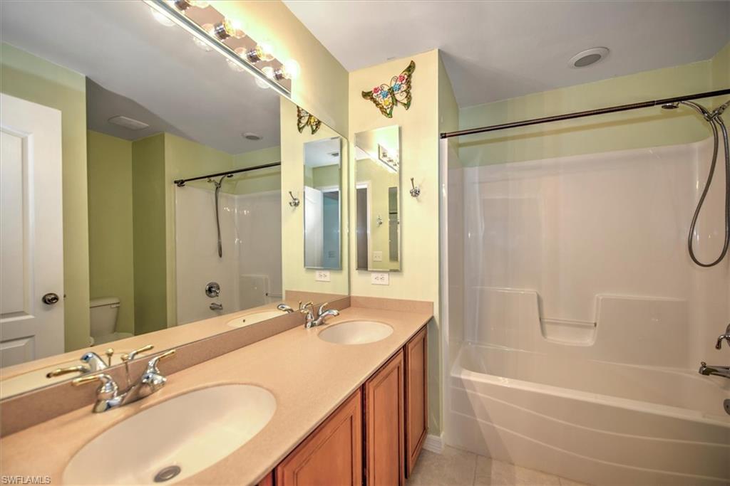 Full 2nd  bathroom with tile floors,  shower combination, vanity with extensive cabinet space, toilet, and dual sinks