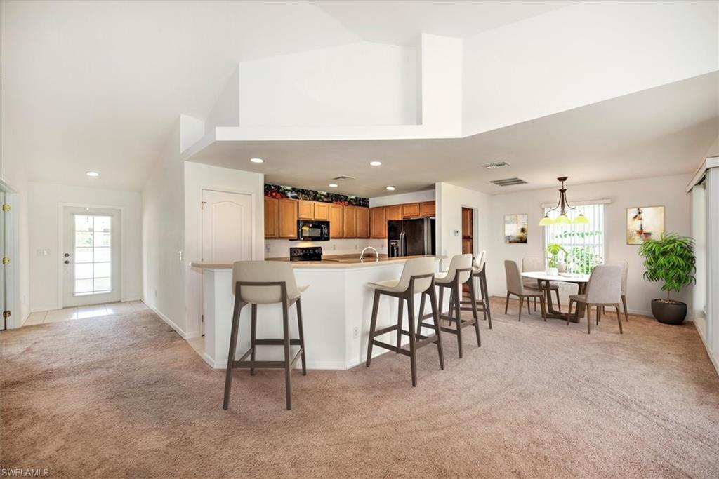 Kitchen Staged featuring light colored carpet, black appliances, and plenty of natural light
