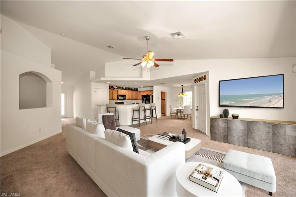 Great Room Staged featuring high vaulted ceiling, light carpet, ceiling fan, and a healthy amount of sunlight