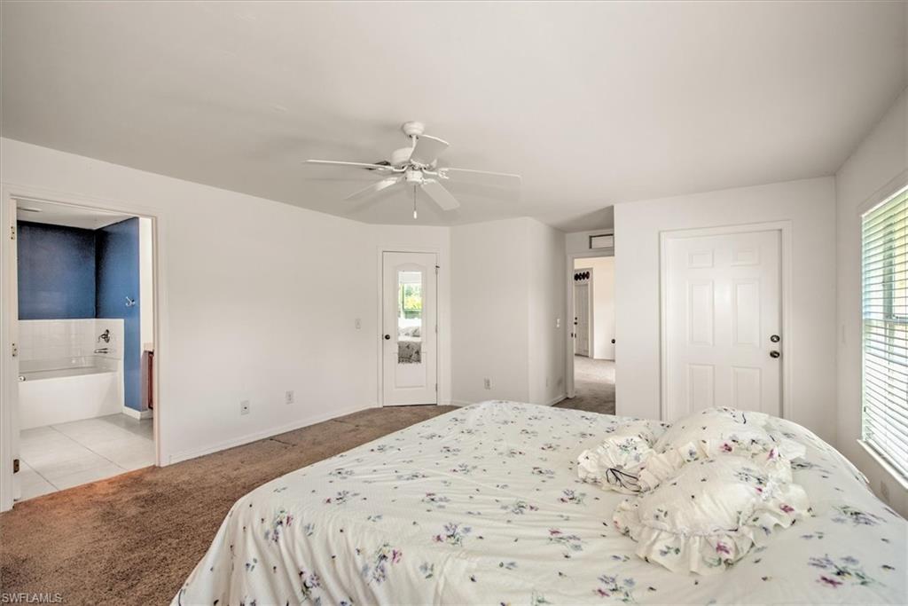 Bedroom with multiple windows, ceiling fan, and ensuite bath