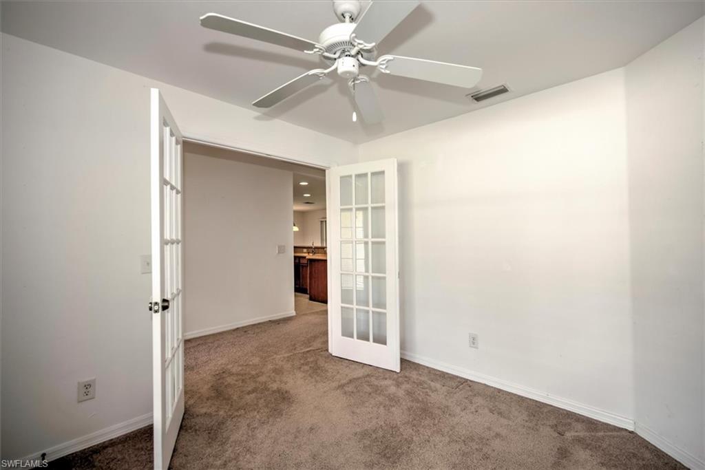 Den with french doors, ceiling fan, and carpet floors